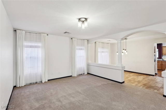 spare room with light carpet and decorative columns