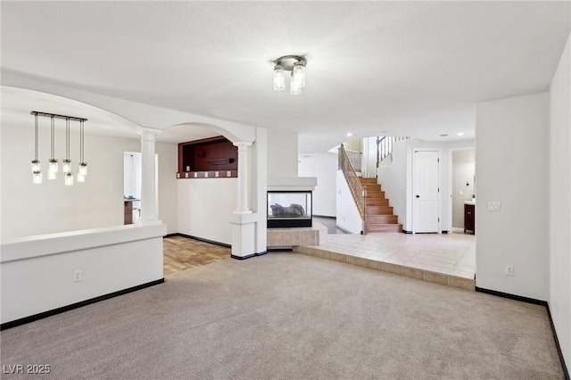 unfurnished living room featuring light colored carpet and decorative columns