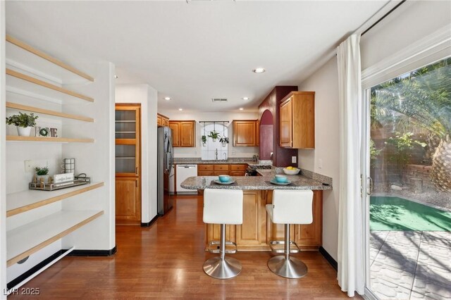 kitchen featuring sink, dishwasher, a kitchen breakfast bar, kitchen peninsula, and dark wood-type flooring