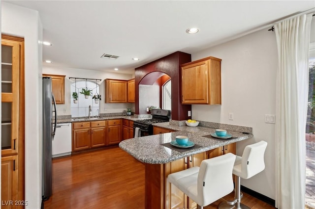 kitchen with kitchen peninsula, a breakfast bar area, white dishwasher, black range with gas stovetop, and sink