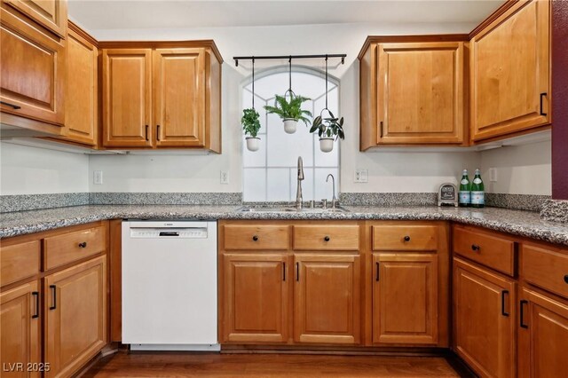 kitchen featuring light stone countertops, dishwasher, dark hardwood / wood-style floors, and sink