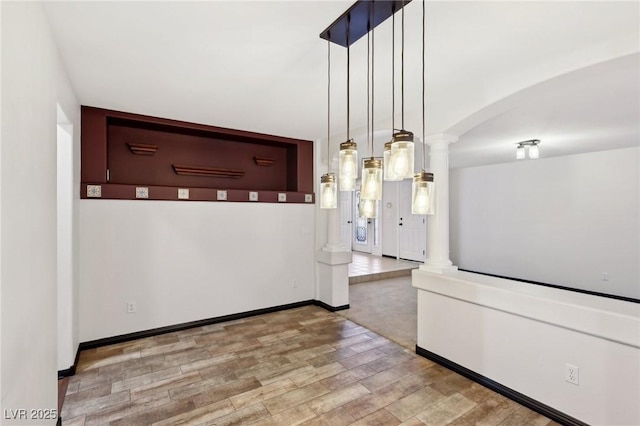 unfurnished dining area featuring ornate columns and hardwood / wood-style flooring