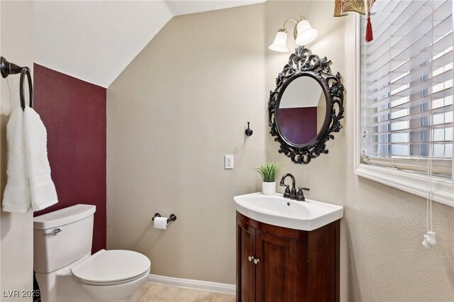 bathroom featuring toilet, vaulted ceiling, and vanity