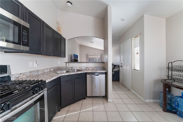 kitchen featuring appliances with stainless steel finishes, light tile patterned flooring, lofted ceiling, and sink