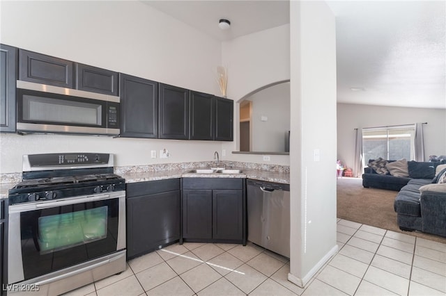 kitchen with sink, stainless steel appliances, light tile patterned flooring, and lofted ceiling