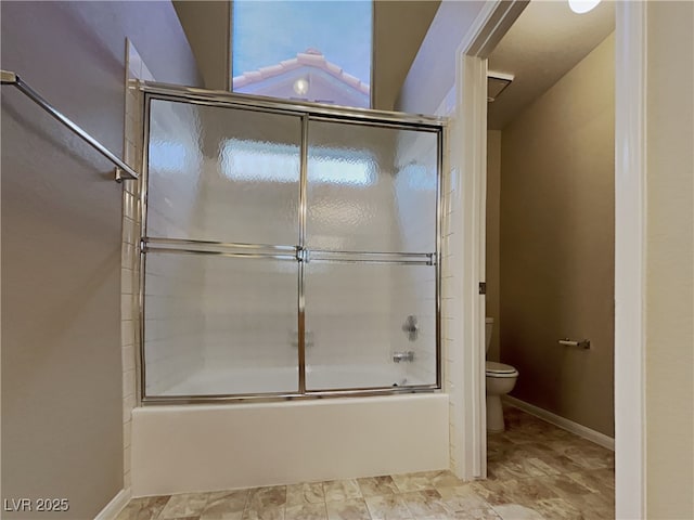 bathroom featuring toilet and combined bath / shower with glass door