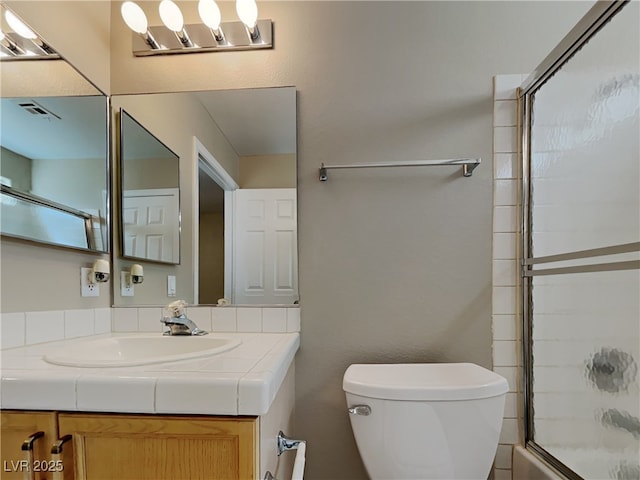 full bathroom featuring toilet, shower / bath combination with glass door, and vanity