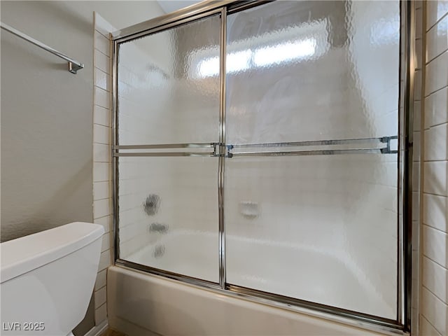 bathroom featuring enclosed tub / shower combo and toilet