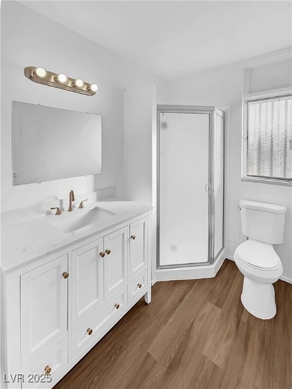 bathroom with toilet, hardwood / wood-style flooring, an enclosed shower, and vanity