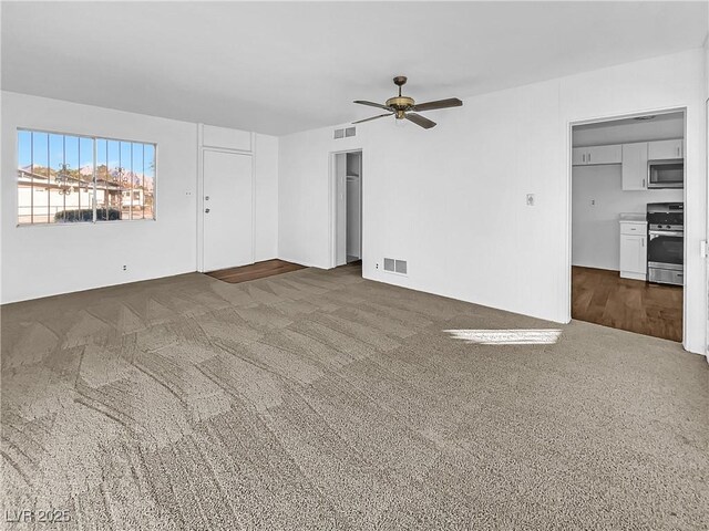 unfurnished living room featuring ceiling fan and dark colored carpet