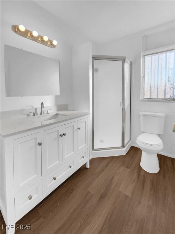 bathroom featuring toilet, a shower with door, vanity, and hardwood / wood-style floors