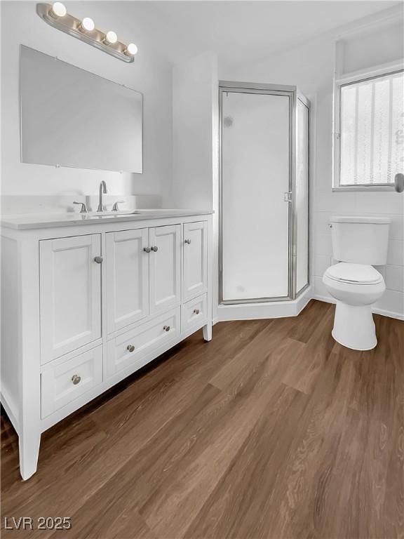 bathroom with toilet, an enclosed shower, vanity, and hardwood / wood-style floors