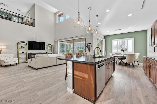 kitchen featuring dishwasher, light hardwood / wood-style flooring, decorative light fixtures, a kitchen island with sink, and sink