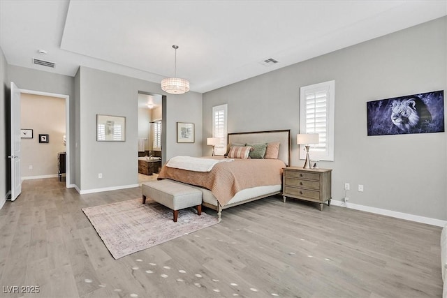 bedroom featuring ensuite bathroom, multiple windows, and light hardwood / wood-style floors