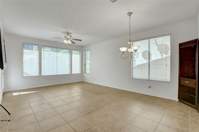 tiled spare room featuring ceiling fan with notable chandelier