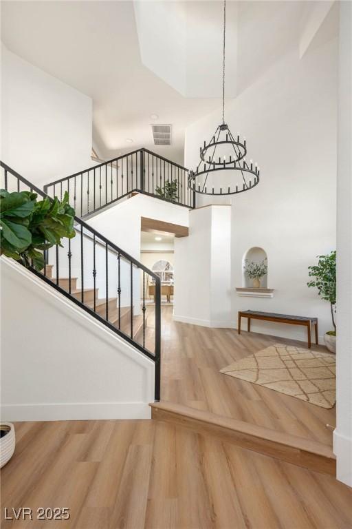 staircase featuring parquet flooring, baseboards, visible vents, and a towering ceiling