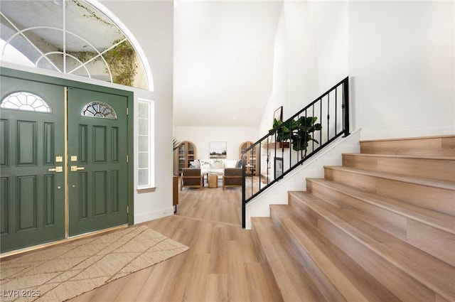 entryway featuring stairway, baseboards, a high ceiling, and wood finished floors