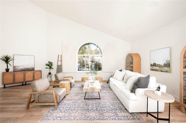 living area featuring lofted ceiling, arched walkways, and light wood finished floors