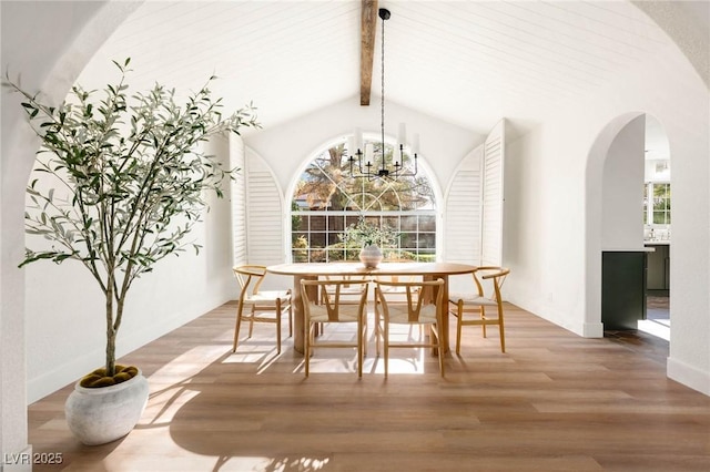 dining space with vaulted ceiling with beams, wood-type flooring, an inviting chandelier, and plenty of natural light