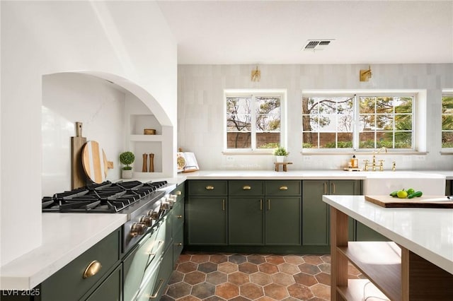 kitchen featuring a healthy amount of sunlight, visible vents, light countertops, stainless steel gas stovetop, and green cabinets