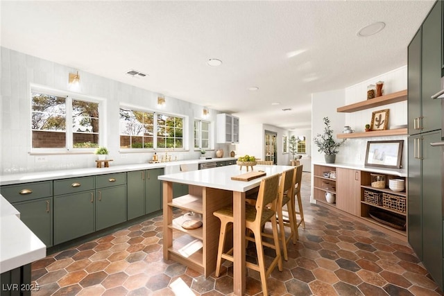 kitchen featuring open shelves, visible vents, green cabinetry, and light countertops