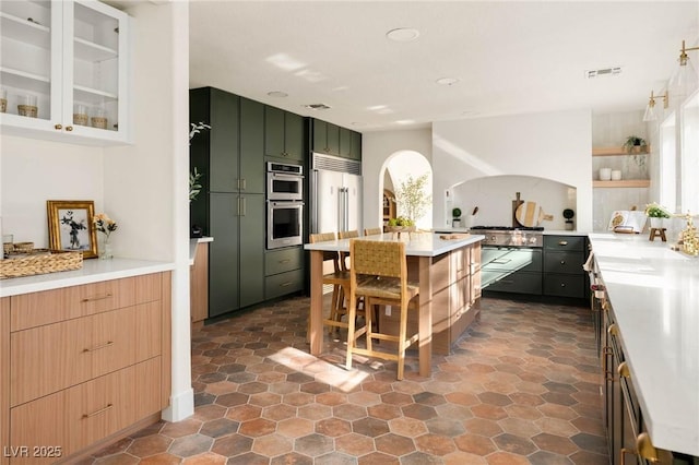 kitchen with visible vents, double oven, light countertops, arched walkways, and built in fridge