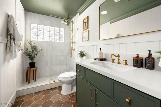 bathroom featuring tile patterned flooring, toilet, vanity, a tile shower, and a textured ceiling