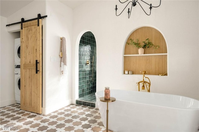 bathroom featuring tile patterned floors, stacked washer and dryer, an inviting chandelier, and a soaking tub