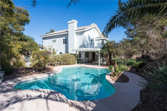 rear view of property featuring a tiled roof, stucco siding, a chimney, an outdoor pool, and a patio