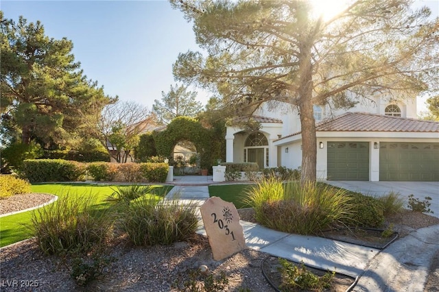 mediterranean / spanish-style house featuring a tile roof, a front yard, stucco siding, a garage, and driveway