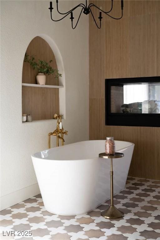 full bath with tile patterned floors, a soaking tub, and a chandelier