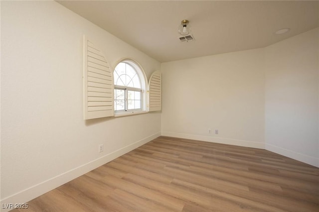 unfurnished room featuring visible vents, baseboards, and wood finished floors