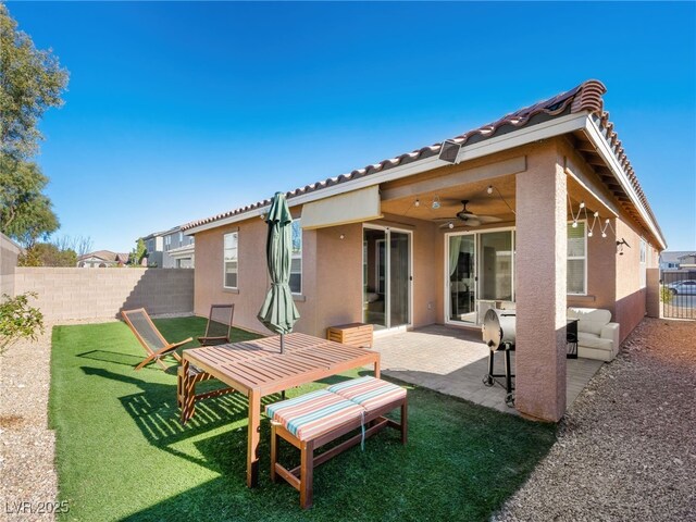 back of property featuring ceiling fan, a lawn, and a patio area