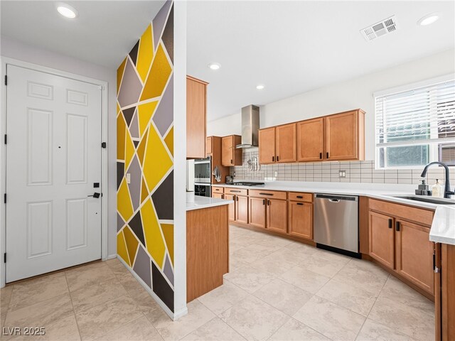 kitchen featuring appliances with stainless steel finishes, sink, backsplash, and wall chimney exhaust hood