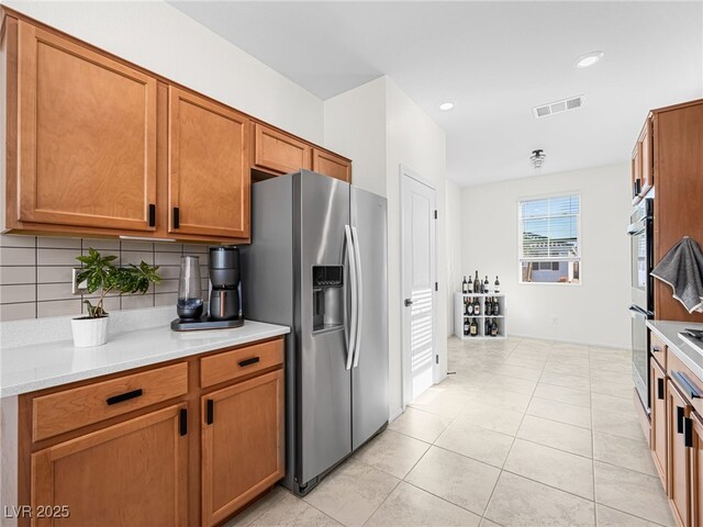 kitchen with light tile patterned flooring, decorative backsplash, and appliances with stainless steel finishes