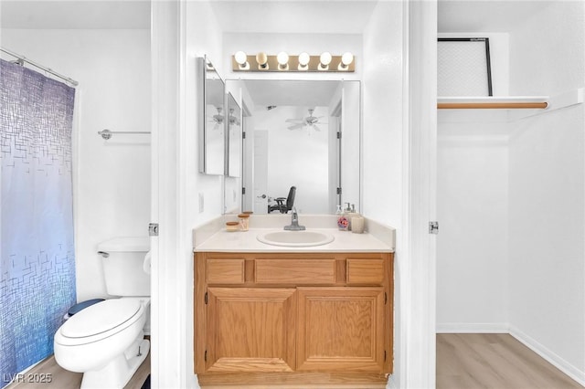 bathroom with toilet, vanity, wood-type flooring, and ceiling fan