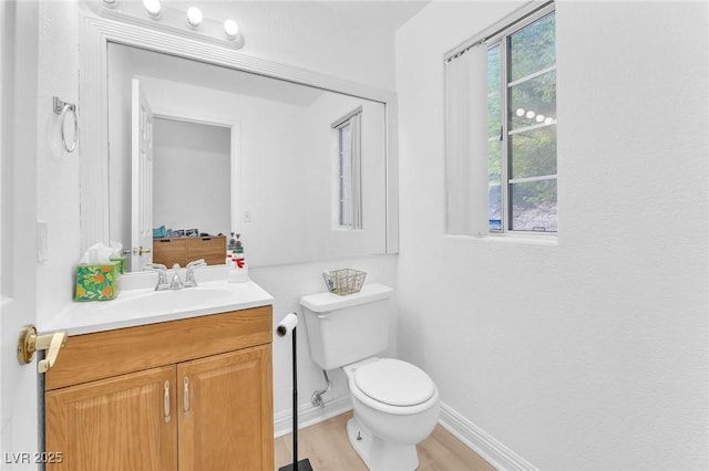 bathroom with toilet, a wealth of natural light, hardwood / wood-style flooring, and vanity