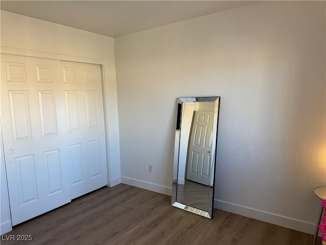 unfurnished bedroom with dark wood-type flooring and a closet