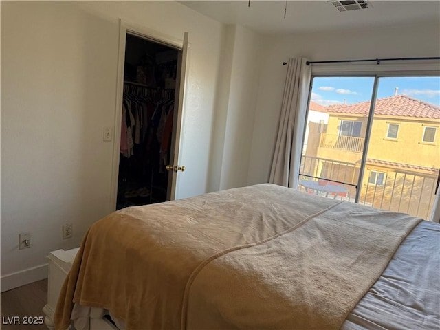 bedroom with a spacious closet, hardwood / wood-style floors, and a closet