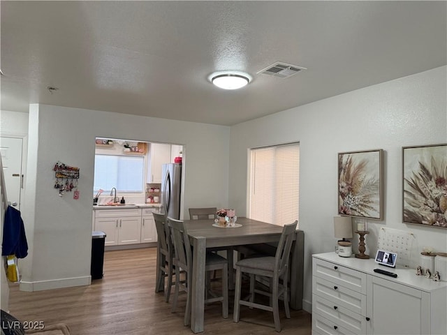 dining area with sink, light wood-type flooring, and a textured ceiling