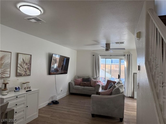 living room featuring hardwood / wood-style flooring, a textured ceiling, and ceiling fan