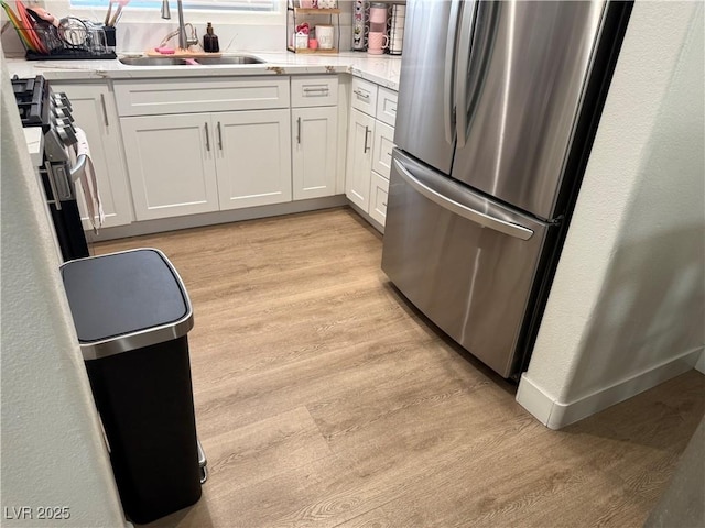 kitchen featuring sink, stainless steel appliances, white cabinetry, and light wood-type flooring