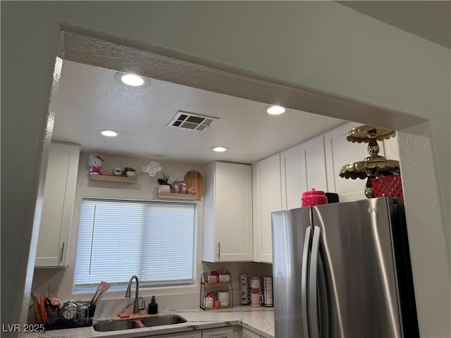 kitchen with sink, white cabinets, a textured ceiling, and stainless steel fridge