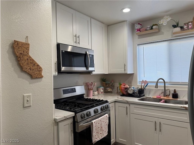 kitchen with sink, stainless steel appliances, white cabinetry, and light stone countertops