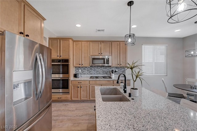 kitchen with sink, stainless steel appliances, and light stone countertops