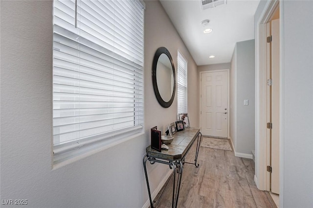 corridor with light hardwood / wood-style floors and plenty of natural light