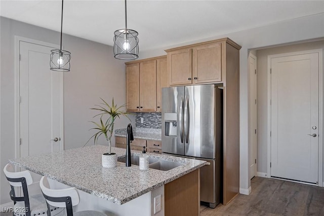 kitchen featuring decorative light fixtures, sink, stainless steel fridge with ice dispenser, backsplash, and light brown cabinets