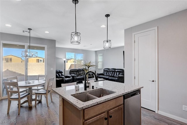 kitchen featuring hanging light fixtures, an island with sink, dark hardwood / wood-style floors, sink, and stainless steel dishwasher