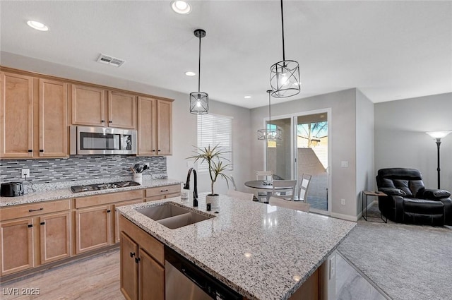 kitchen with decorative light fixtures, a center island with sink, tasteful backsplash, appliances with stainless steel finishes, and sink