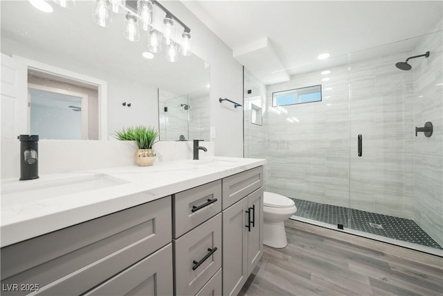 bathroom with toilet, hardwood / wood-style flooring, a shower with door, and vanity